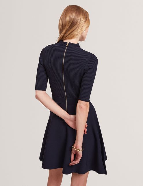 Woman wearing a navy blue dress with a plain background